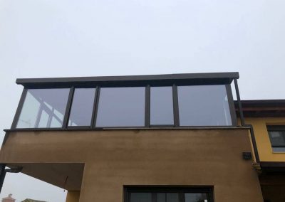 Cerramiento de aluminio en una terraza abierta, con cristales de seguridad, bajo emisivos, carpintería de aluminio color marrón con bajante incluida